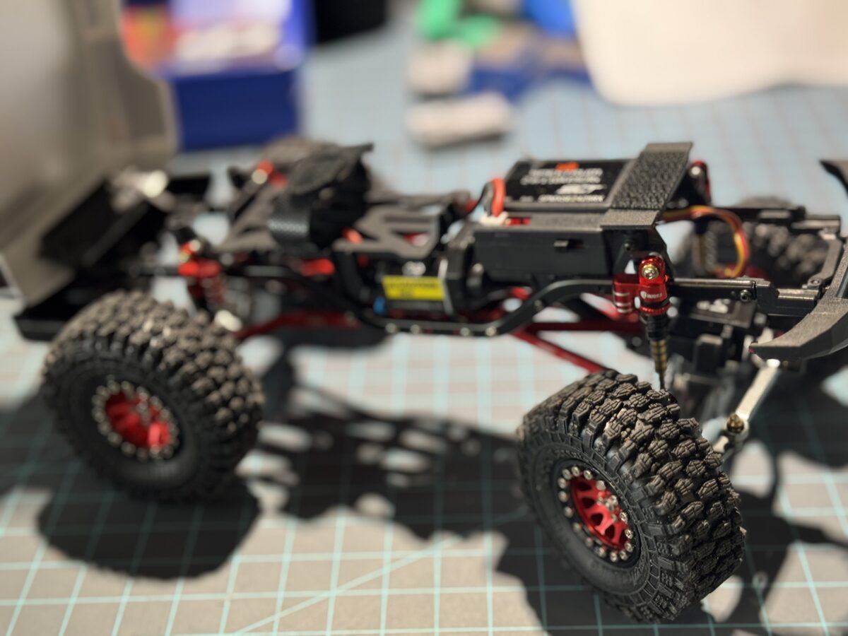 SCX24 stripped chassis showing red shocks and metal links